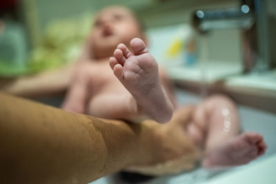 Cropped hand of mother holding baby girl in bathtub