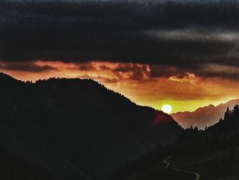 Scenic view of silhouette mountains against dramatic sky