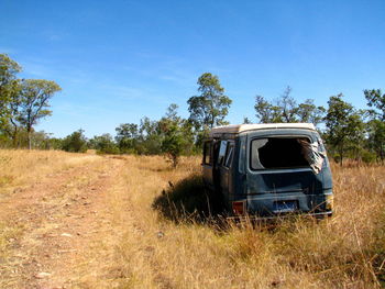 Abandoned truck on field against blue sky