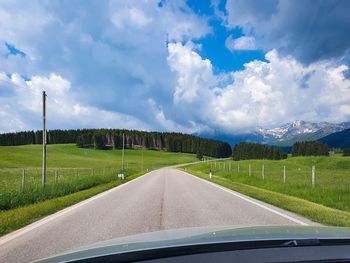 Road amidst field against sky