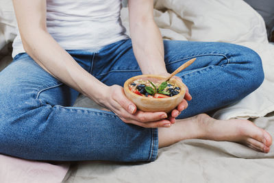 Midsection of woman holding apple while sitting on bed