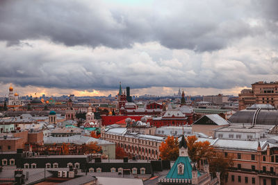 Aerial view of buildings in city against cloudy sky