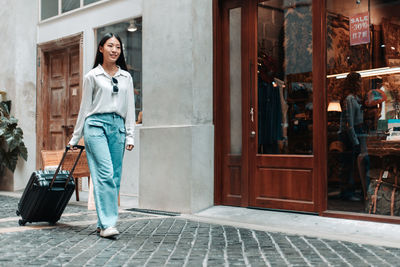 Portrait of smiling woman standing against the wall