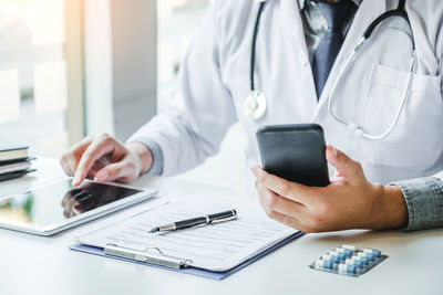 Midsection of man using mobile phone on table