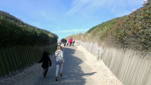 People walking on footpath by mountain against sky