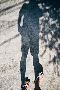 Low section of man standing on footpath with shadow