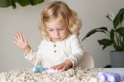 Portrait of girl playing with sand at home