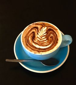Close-up of cappuccino served on table against black background