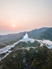 Buddha statue on mountain against sky during sunset