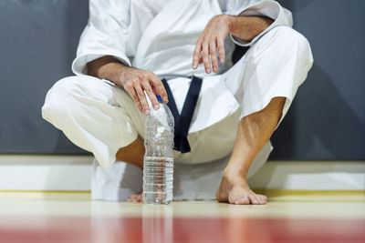 Exhausted mature man holding water bottle in class