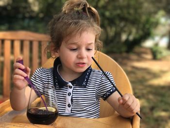 Baby girl having soda while sitting on chair