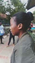 Side view of young woman looking away while standing on street