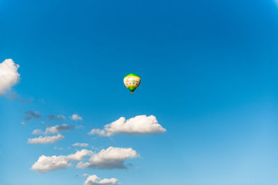Low angle view of hot air balloon flying against blue sky