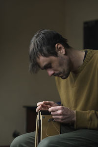 Young man looking away while sitting on floor