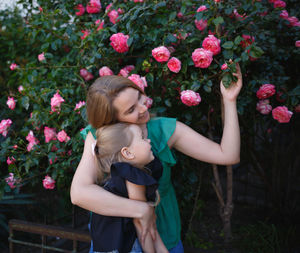 Mother and daughter touching flowers outdoors