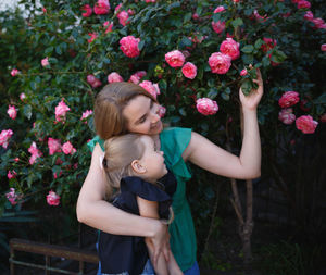 Beautiful woman standing by pink flowering plants