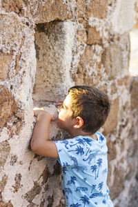 Rear view of boy on rock against wall