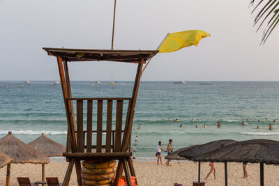 Deck chairs on beach against sky