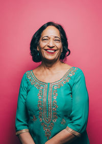 Portrait of smiling senior woman wearing salwar kameez on pink background