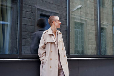 Woman looking away while standing against window