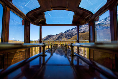 Reflection of bridge on mountain against sky seen through window