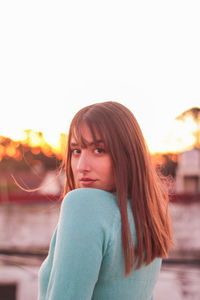 Portrait of young woman looking away against sky