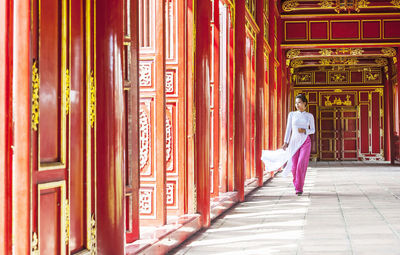 Rear view of woman walking in temple against building