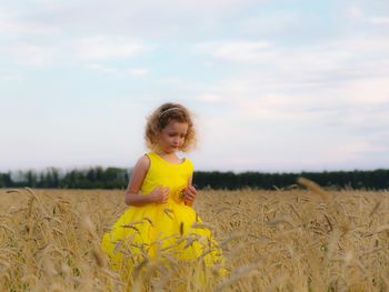 Girl standing on field against sky