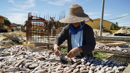 Woman selling fishes at market against sky