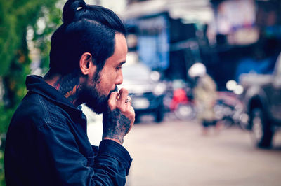 Side view of young man looking away on city street