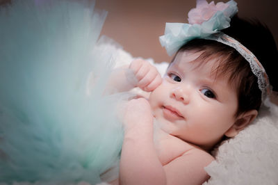 Close-up portrait of cute baby girl lying on bed