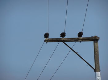 Low angle view of electricity pylon against clear sky