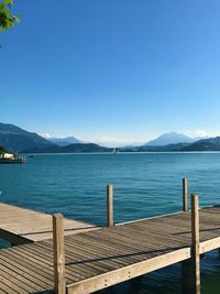 Pier over sea against clear blue sky