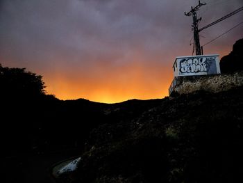 Low angle view of road sign against sky at sunset