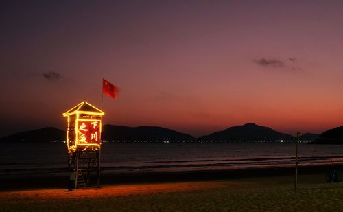 Lifeguard hut on beach against sky during sunset