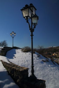 Snow covered street light against clear blue sky