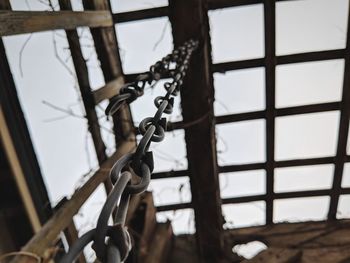 Low angle view of chain hanging against window