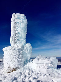 Snow on landscape against blue sky
