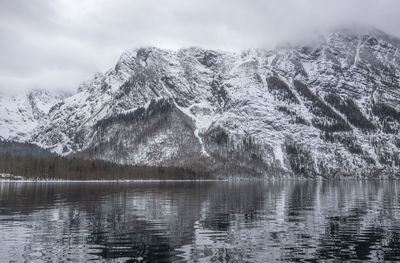 Scenic view of lake by snowcapped mountains against sky