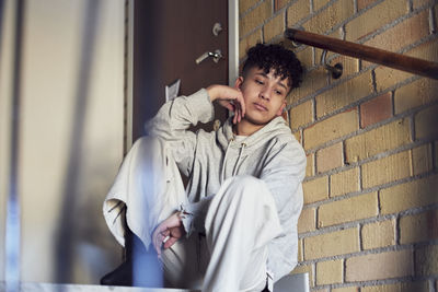 Boy sitting on stairs and leaning against wall