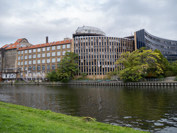 Buildings by river against sky