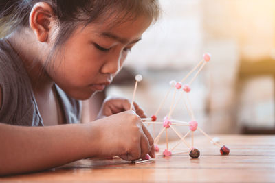 Cute girl making molecule model on wooden table in porch