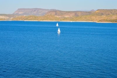 Sailboat in sea against blue sky