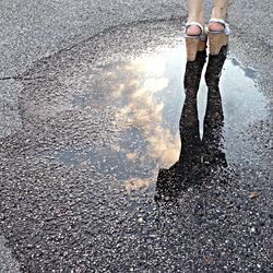 Low section of woman standing in puddle