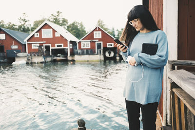 Woman using smart phone while standing by lake