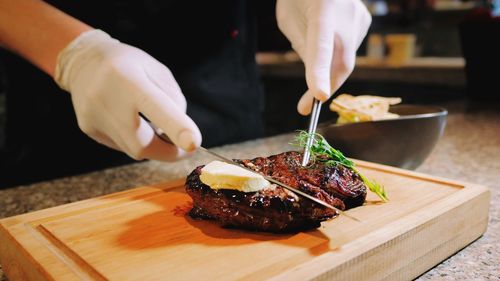 Midsection of chef cutting meat on table