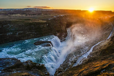 Scenic view of waterfall against sky during sunset