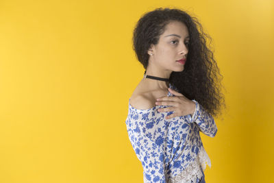 Portrait of a young woman against yellow background