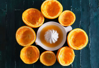 Still life on a green wooden base of an orange squeezer with orange ju