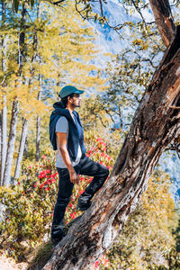 Full length of man standing by tree in forest during autumn